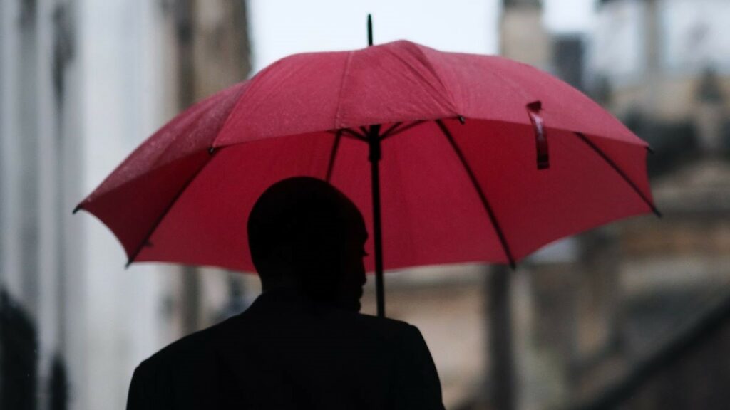 Business insurance represented by a businessman holding a red umbrella