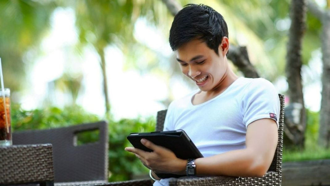 smiling Asian man introducing his brand to a new market on an electronic device