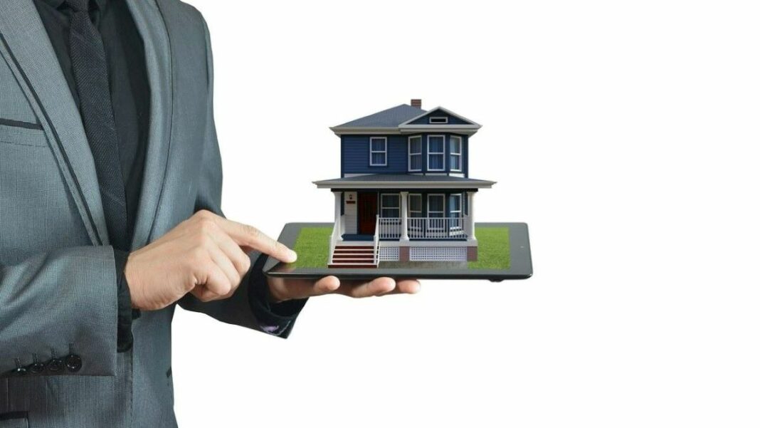 real estate seo represented by a model of a house on a tablet with a man's hand pointing to it