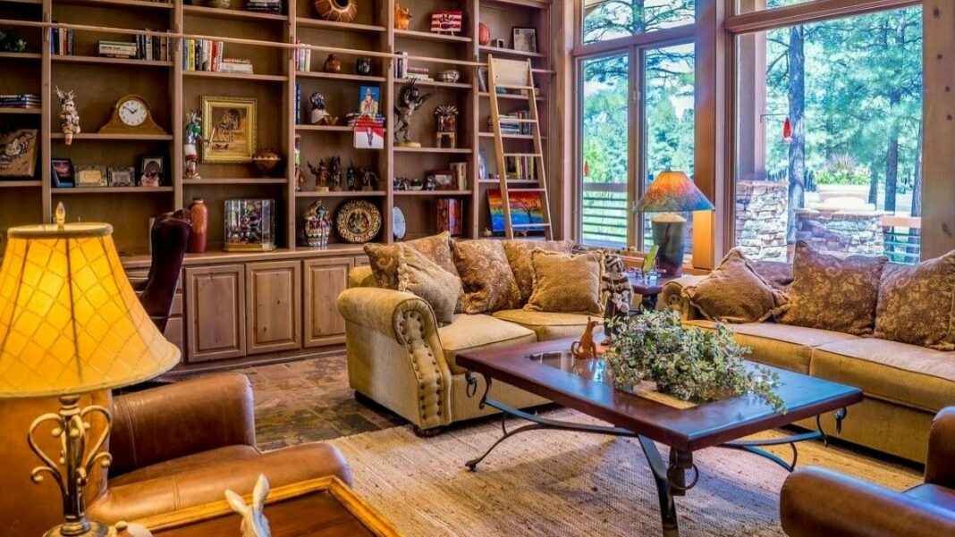 Buying a house can let you design a sitting room like this one with a beautiful view that's filled with books and some comfortable couches and chairs.