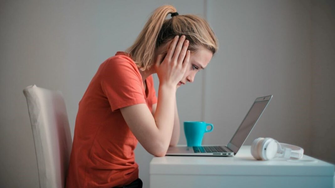 Young businesswoman upset about her suspended Google Ads account, sitting in front of her laptop with her head in her hands