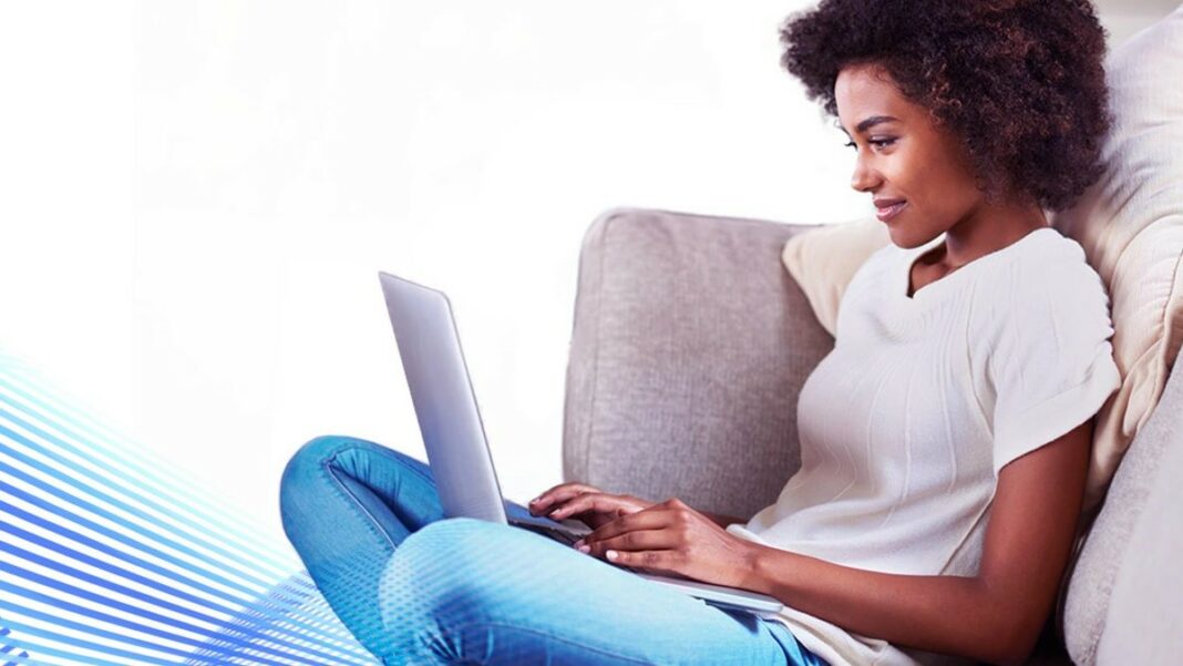 write an essay represented by a woman smiling as she types on a laptop while sitting comfortably on a couch