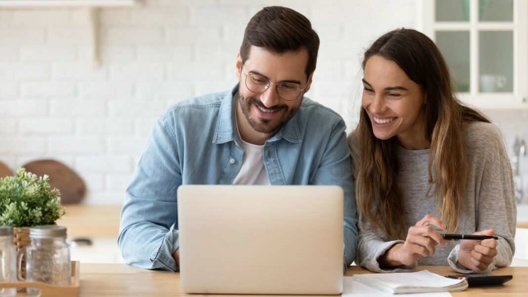 financial apps represented by a happy young couple looking at an open laptop and planning a budget