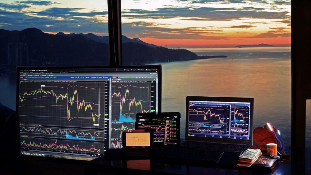 fintech and cryptocurrency represented by an array of devices with screens showing technical tools such as those used by fintech and cryptocurrency traders against the background of a colorful sunset