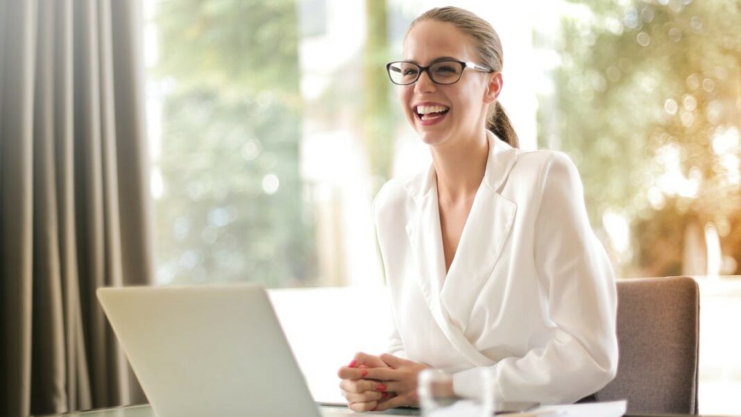 job represented by a laughing businesswoman sitting in front of a laptop
