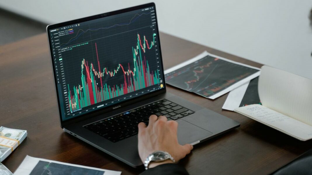 cfd trading represented by a man's hand resting on the keyboard of a laptop displaying a trading chart