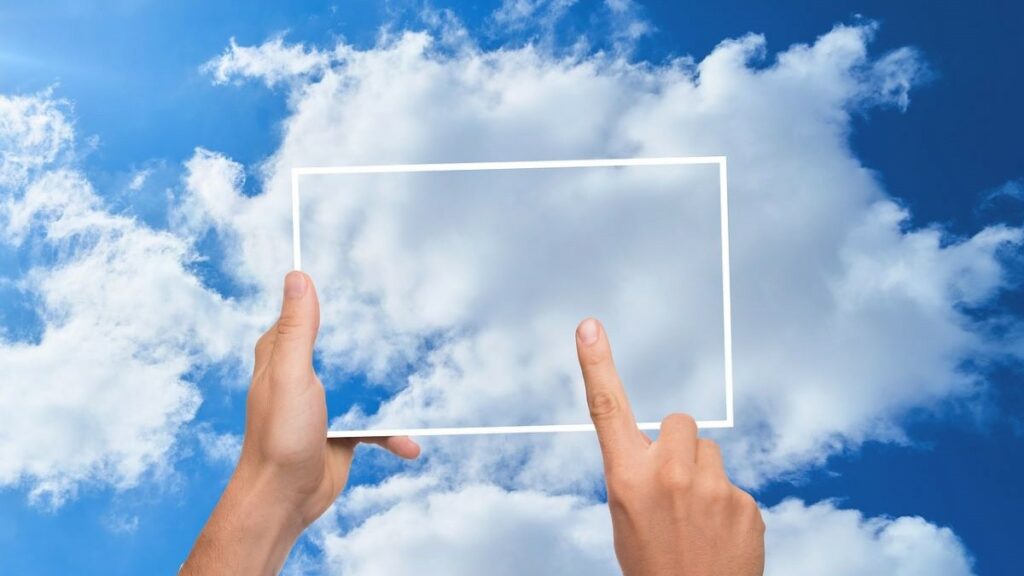 cloud server represented by two hands holding a transparent frame against clouds in blue sky
