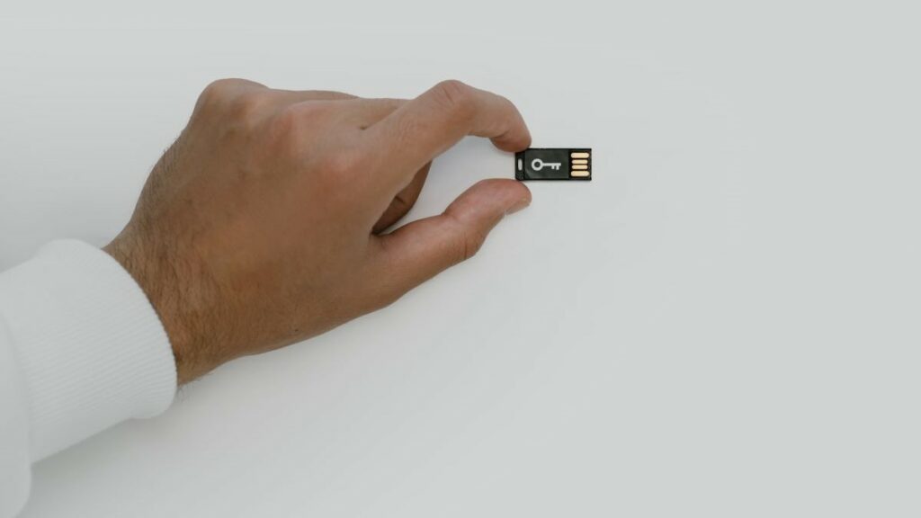 digital security represented by a man's hand holding a USB flash drive imprinted with the image of a key