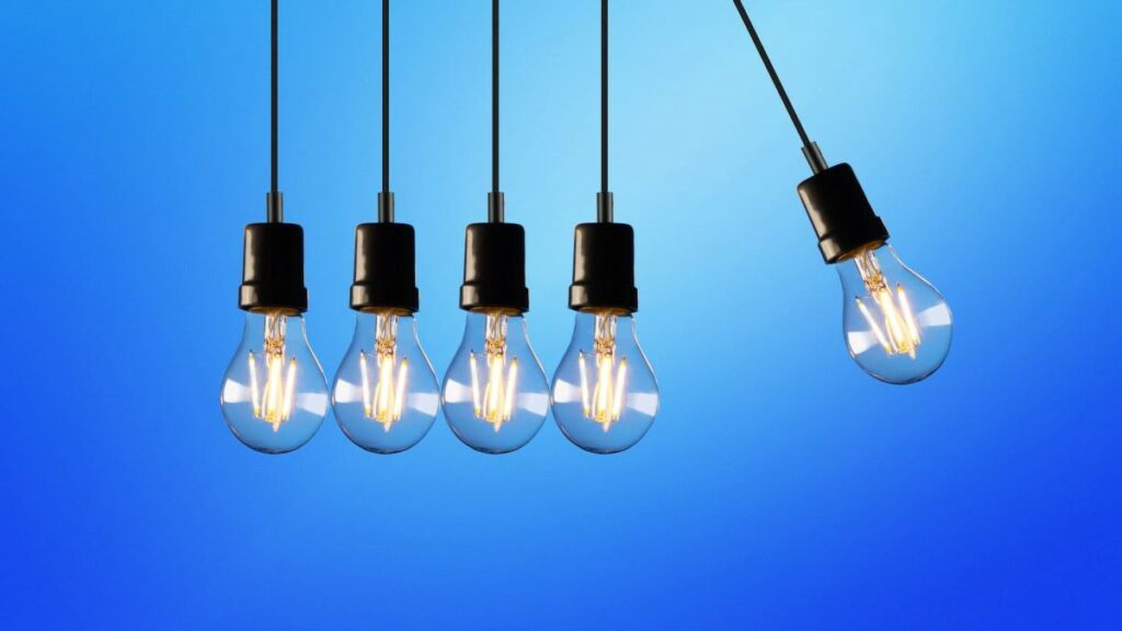 energy efficiency represented by light bulbs suspended by cords over a blue background