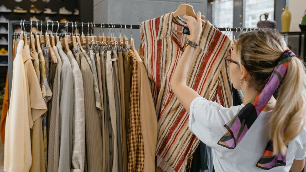 physical business represented by a woman in a retail store arranging blouses for sale