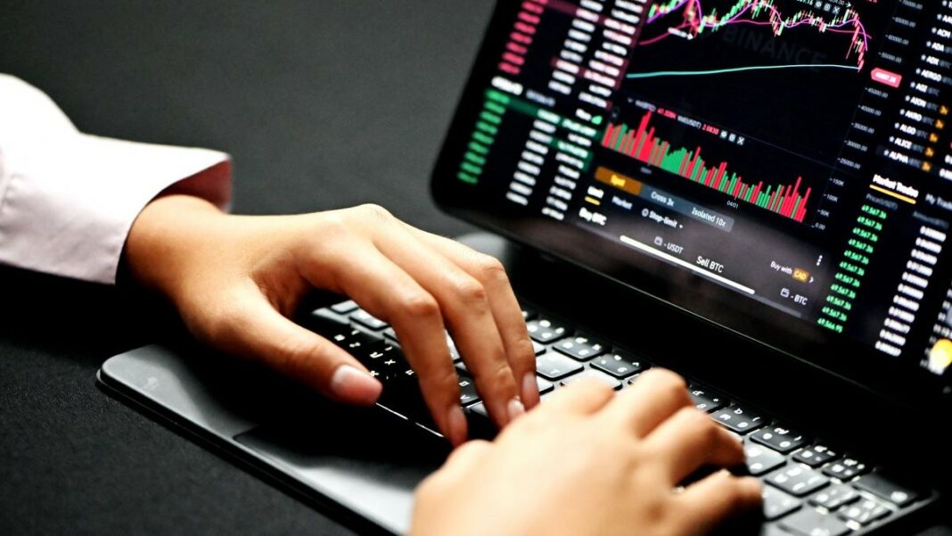 trading affiliate represented by a woman's hands on a laptop displaying trading charts