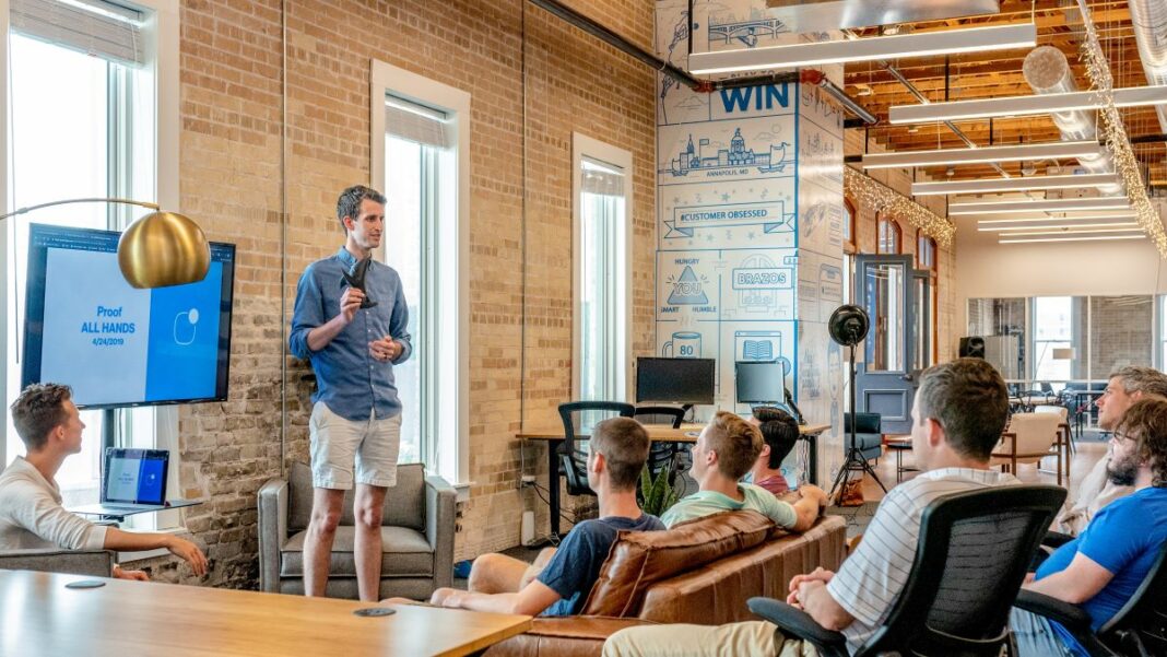 fund your startup represented by a small group of men in casual clothing listening to a man in a blue shirt and shorts