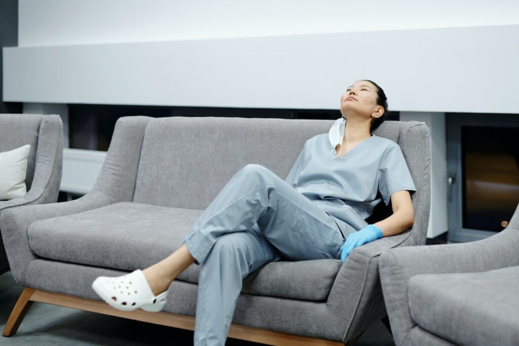 overworked, tired physician resting on couch in her medical practice