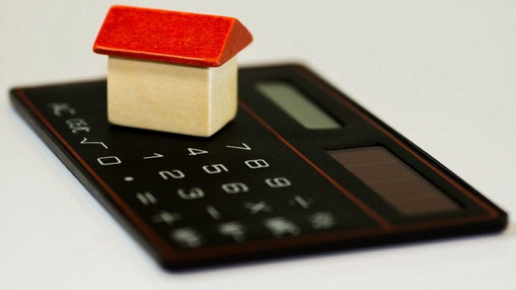 bank rate represented by a toy house sitting on a calculator