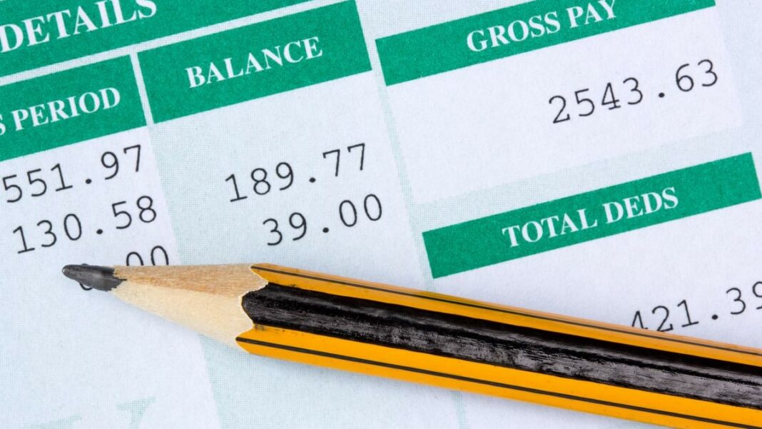 close-up photo of a payslip and a pencil