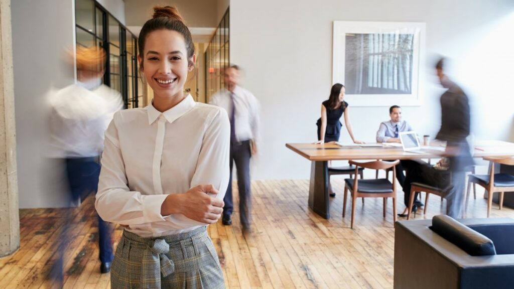 business functions represented represented by a smiling businesswoman in a busy office
