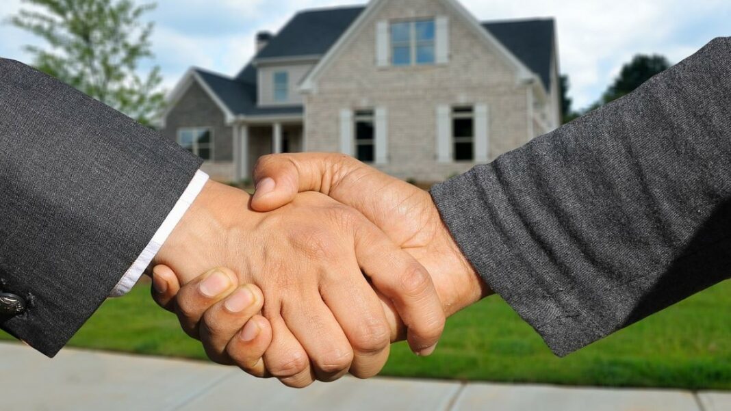 Patrick Carroll's spirit of generosity represented by photo of a handshake between two men in front of a house