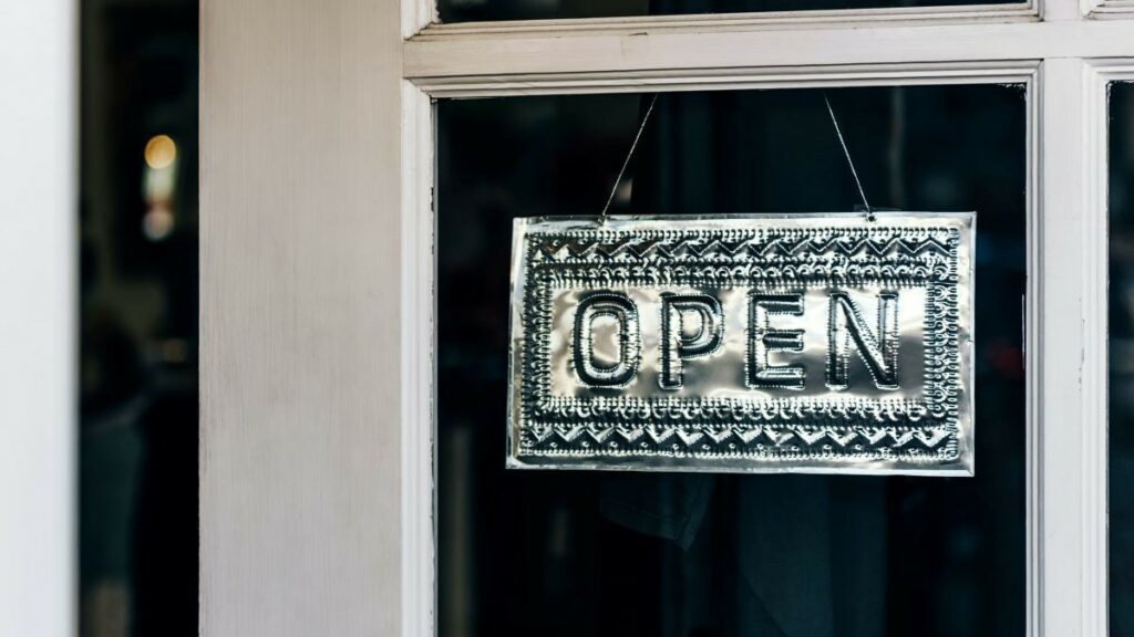 UK small business directories represented by a hammered metal sign reading "Open" hanging in the doorway of a small business