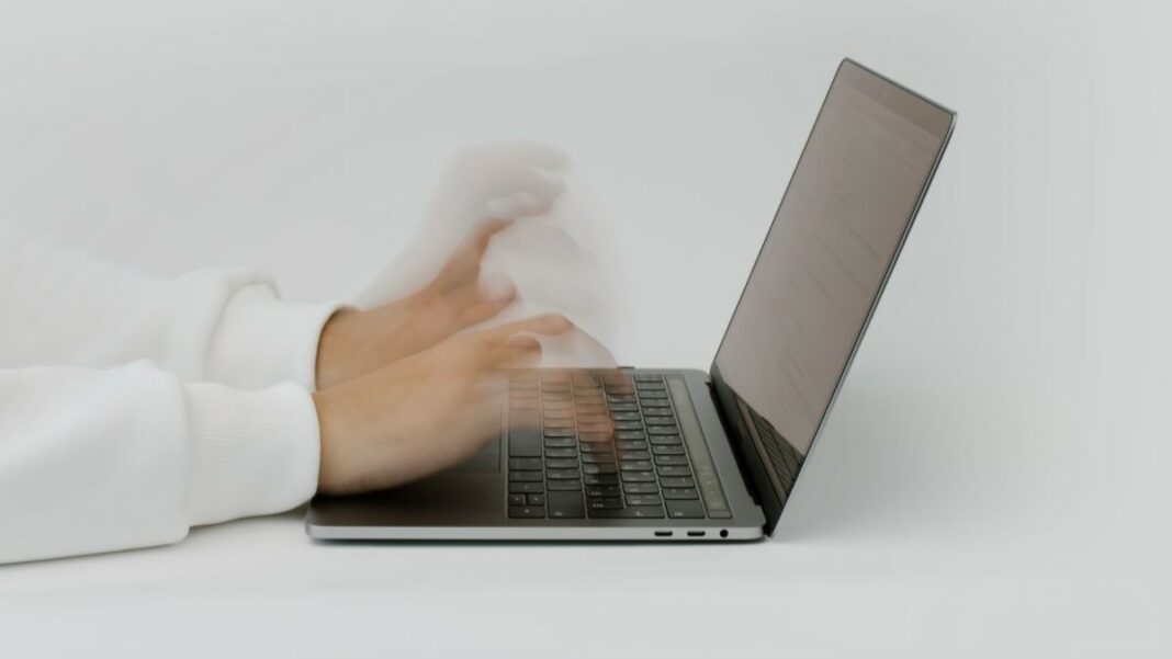 cloud costs represented by a pair of hands typing rapidly on a laptop keyboard against a white background