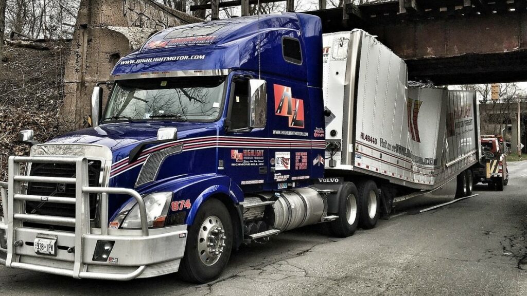 a truck accident in Houston represented by a photo of a big rig whose trailers are caught under a bridge