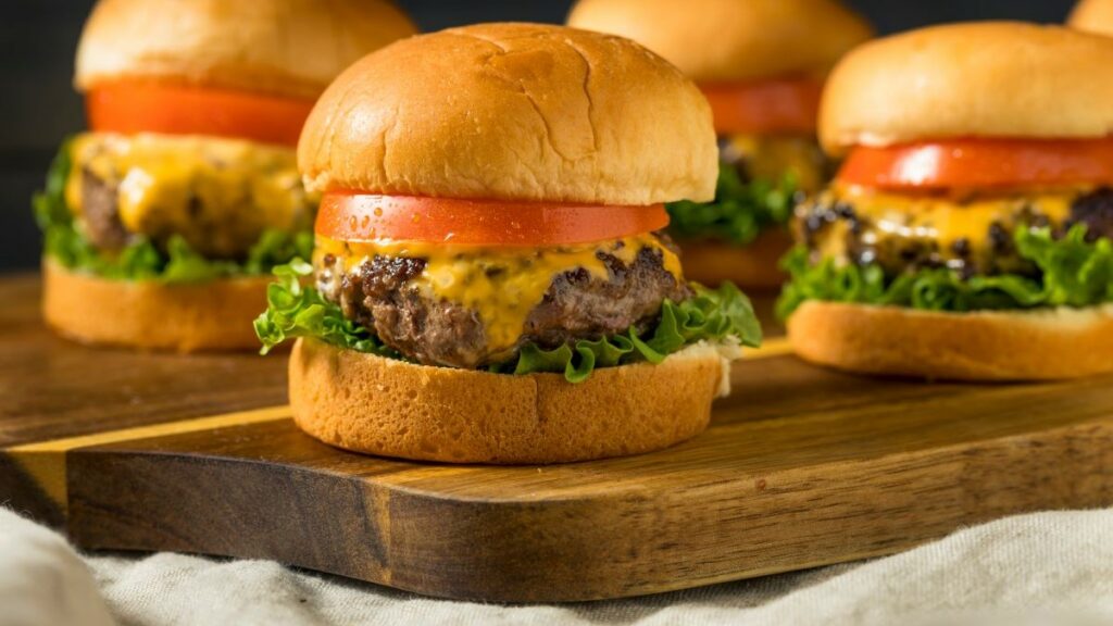 omaha productions represented by a close-up photo of some sliders with cheese, tomato slices, and lettuce