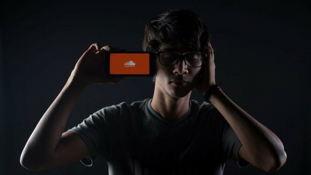 SoundCloud represented by a young man listening to music on a smartphone