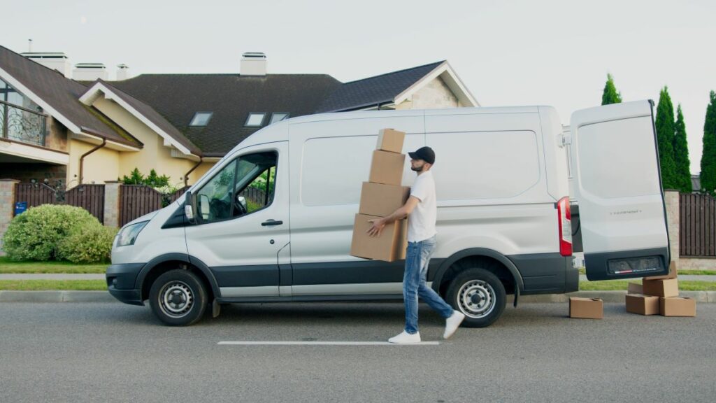 shipping process represented by a photo of a man carrying boxes from a white van toward a residence