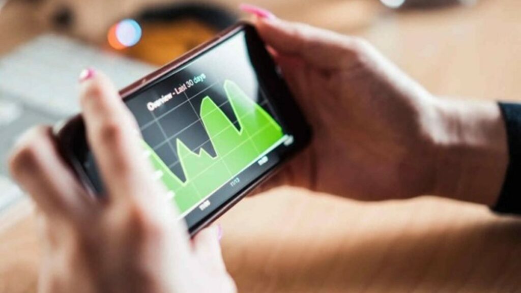stocks and forex represented by a woman's hands as she reviews trading charts on a smartphone