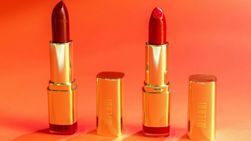 a product ad for red lipsticks in gold-colored tubes against an orange background