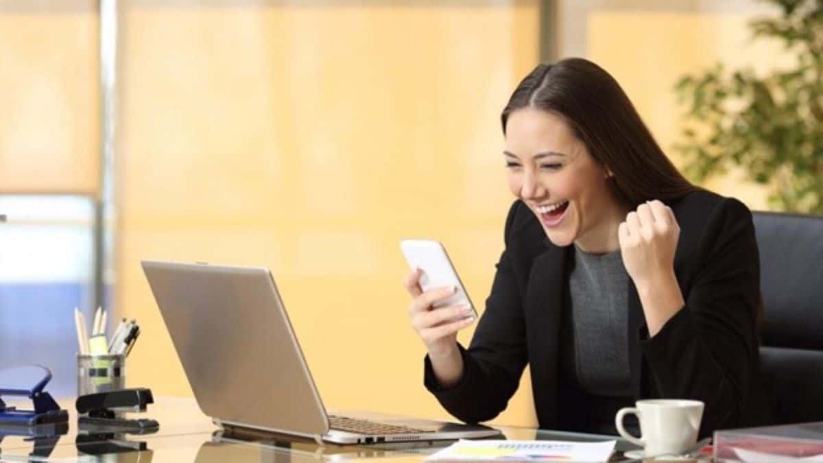 B2B cold calling represented by a businesswoman smiling at the screen of a smartphone