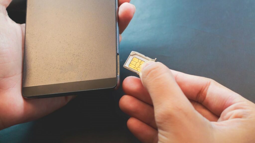 a SIM swap represented by a person's hands inserting a SIM card into a smartphone